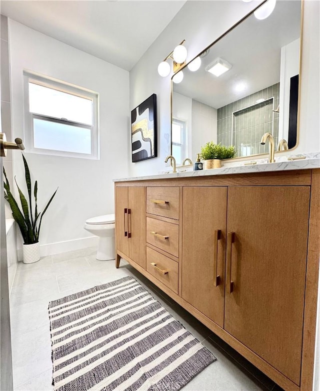 full bathroom featuring double vanity, baseboards, toilet, tile patterned floors, and a sink