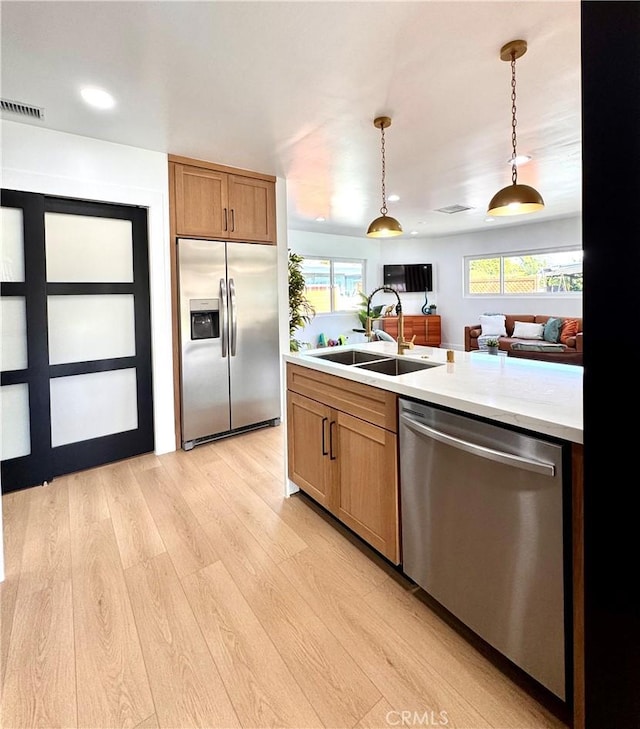 kitchen featuring a sink, visible vents, hanging light fixtures, appliances with stainless steel finishes, and light countertops