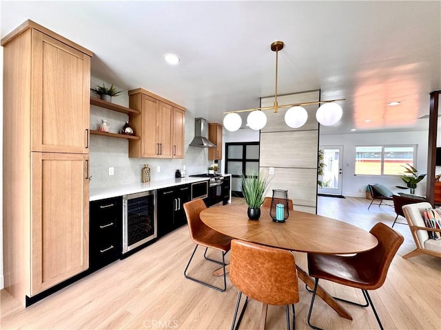 kitchen with open shelves, light countertops, hanging light fixtures, wall chimney range hood, and beverage cooler