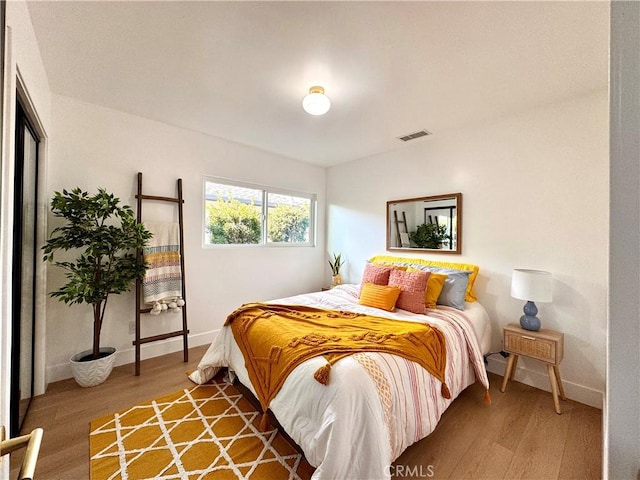 bedroom featuring visible vents, baseboards, and wood finished floors