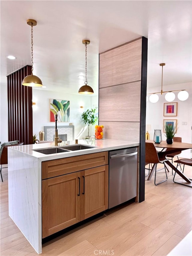 kitchen with pendant lighting, light countertops, brown cabinetry, a sink, and dishwasher