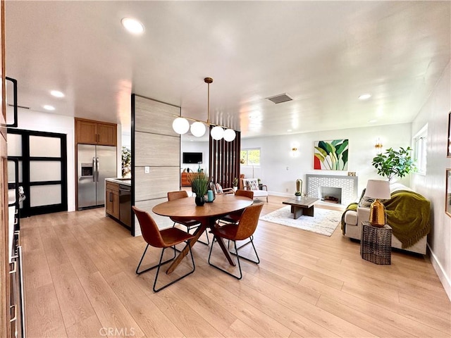 dining space with a fireplace, recessed lighting, visible vents, light wood-style floors, and baseboards