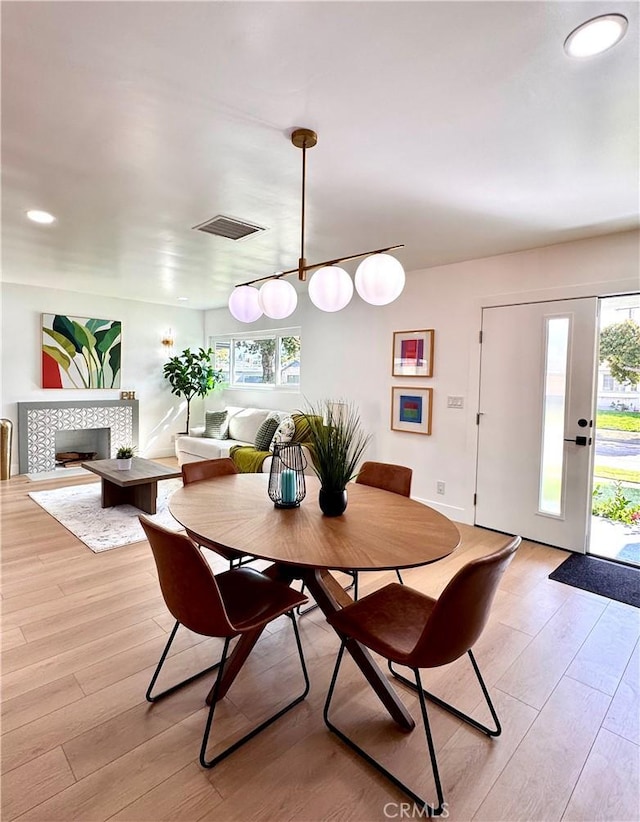 dining room with light wood-style flooring, recessed lighting, a fireplace, visible vents, and baseboards