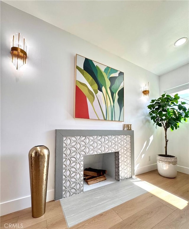 interior space featuring a tile fireplace, baseboards, and wood finished floors