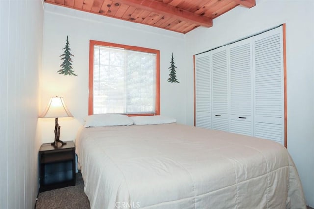 carpeted bedroom featuring wooden ceiling, a closet, and beamed ceiling