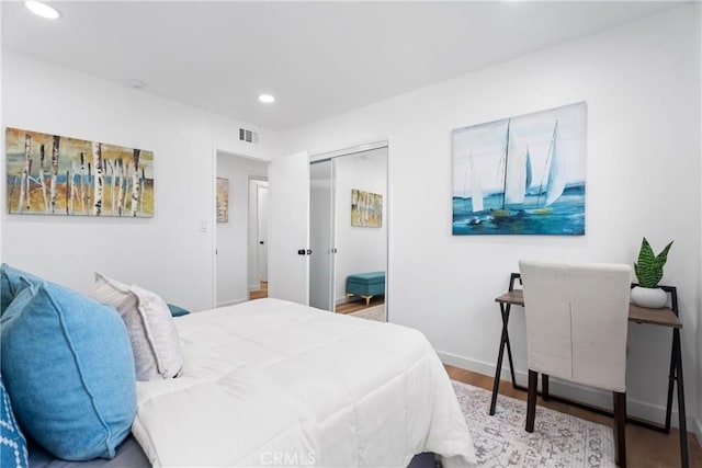 bedroom featuring recessed lighting, wood finished floors, visible vents, baseboards, and a closet