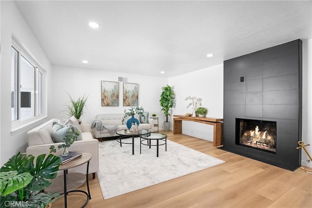 living room featuring a fireplace, visible vents, wood finished floors, and recessed lighting