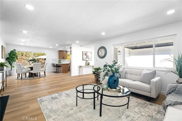 living area with light wood-type flooring, a textured ceiling, and recessed lighting