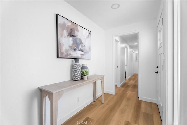 hall featuring light wood-style flooring and baseboards