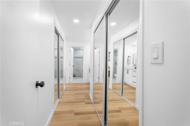 corridor featuring baseboards, wood finished floors, and recessed lighting