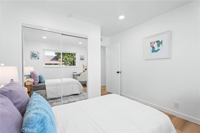 bedroom with a closet, baseboards, wood finished floors, and recessed lighting