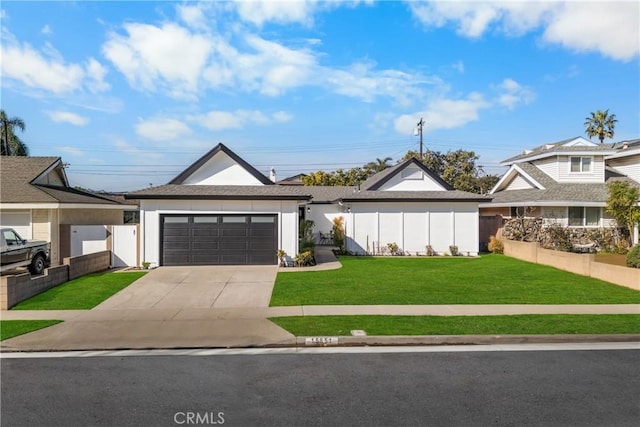 view of front of home with an attached garage, driveway, a front lawn, and fence