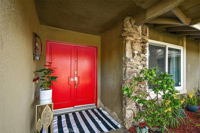 view of exterior entry with stone siding and stucco siding