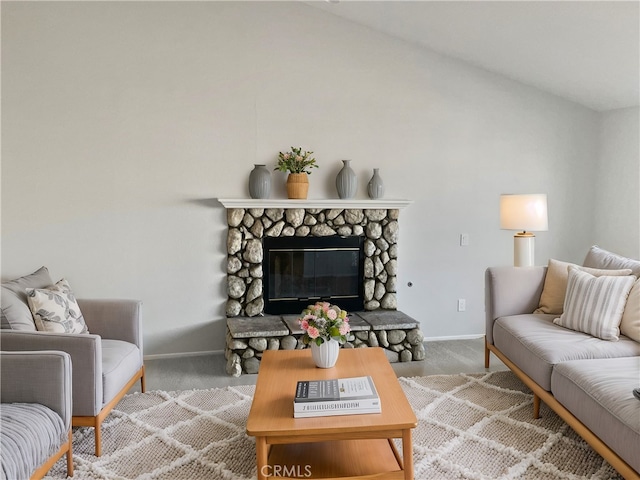 living room with lofted ceiling, a stone fireplace, carpet flooring, and baseboards