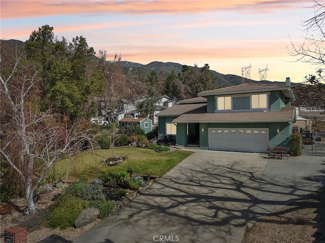 view of front of house with a yard, stucco siding, concrete driveway, an attached garage, and a mountain view