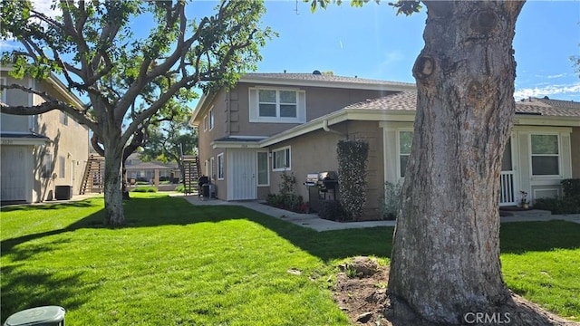 view of side of home with a yard, stairway, and stucco siding