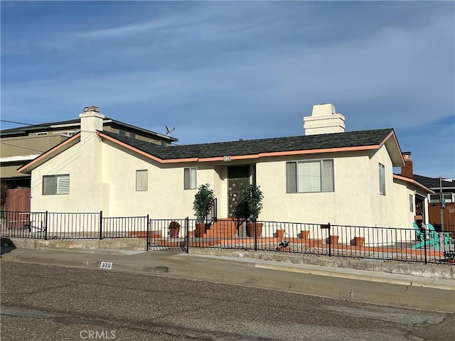 view of front of home with fence, a chimney, and stucco siding