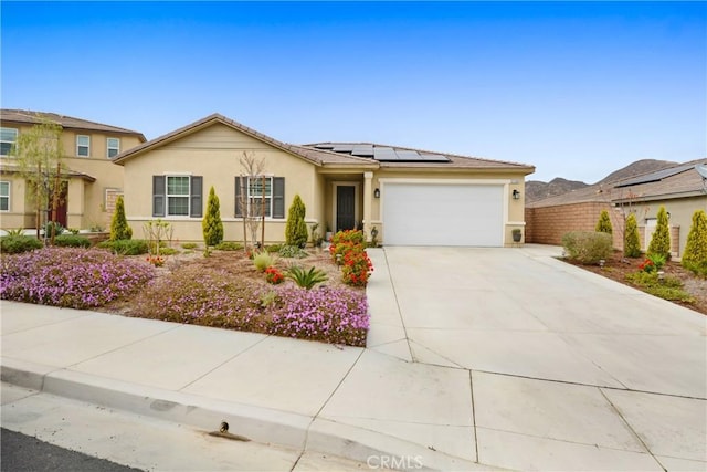 single story home featuring a garage, stucco siding, driveway, and solar panels