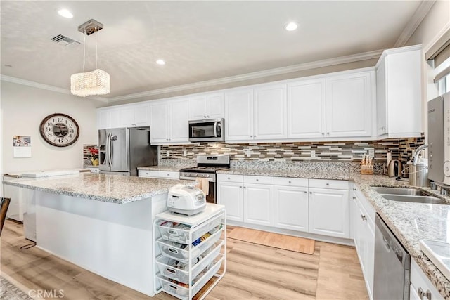 kitchen with visible vents, appliances with stainless steel finishes, crown molding, white cabinetry, and pendant lighting