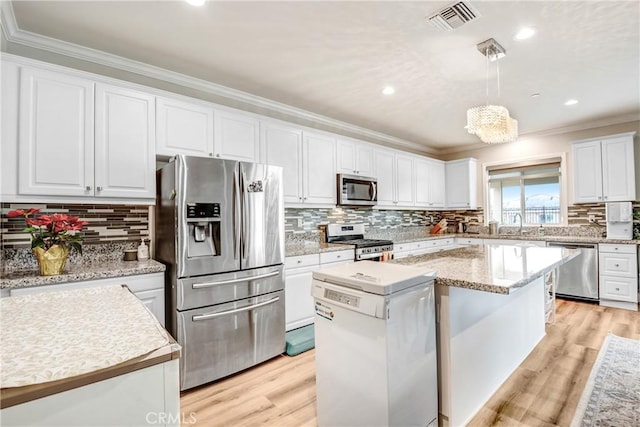 kitchen featuring decorative light fixtures, appliances with stainless steel finishes, white cabinetry, and a center island