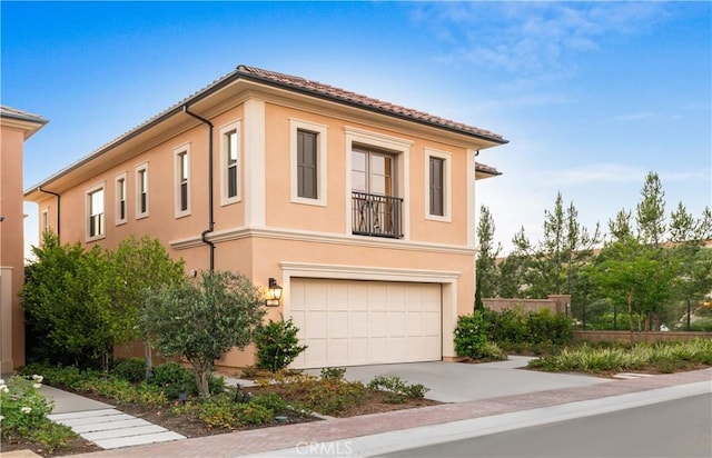 view of side of home featuring driveway, an attached garage, a tile roof, and stucco siding