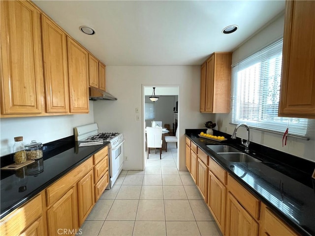 kitchen featuring light tile patterned floors, white gas stove, under cabinet range hood, a sink, and brown cabinetry