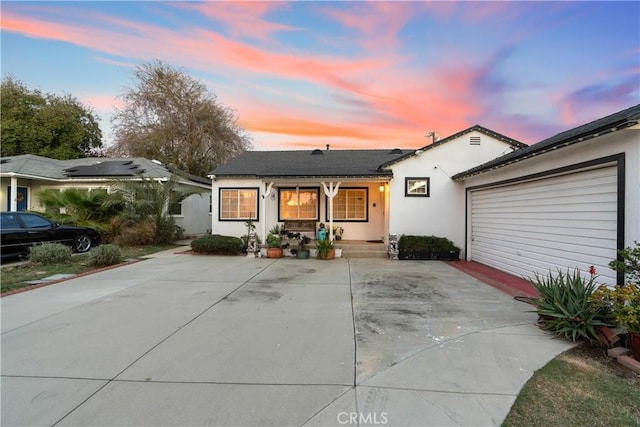 view of front of house featuring driveway, a garage, a porch, and stucco siding