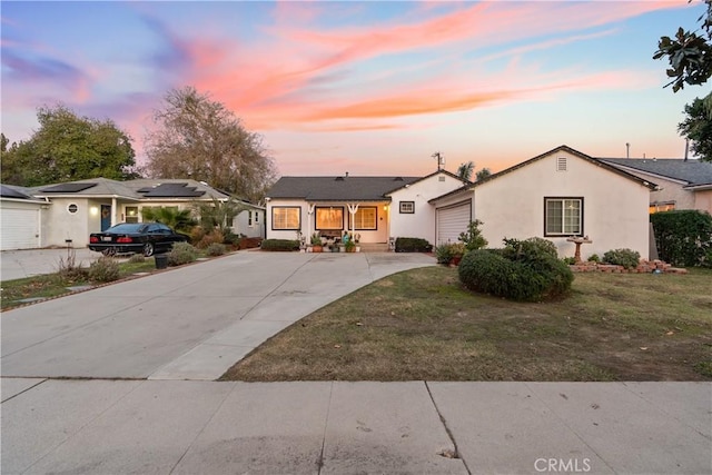 single story home featuring a garage, driveway, a lawn, and stucco siding