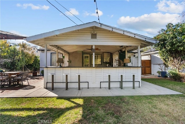 rear view of house with a yard, a patio, a bar, and a ceiling fan