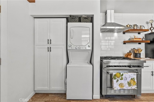 washroom featuring laundry area, wood finished floors, and stacked washer / drying machine