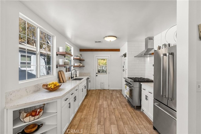 kitchen featuring open shelves, high end appliances, light countertops, white cabinetry, and wall chimney exhaust hood