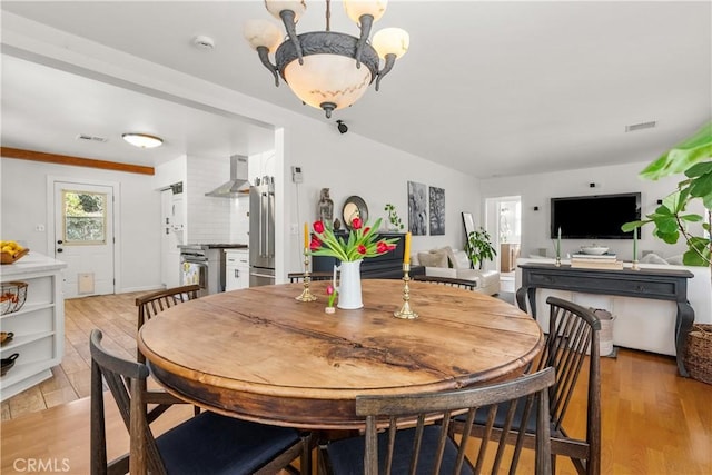 dining room with light wood finished floors, visible vents, and a notable chandelier