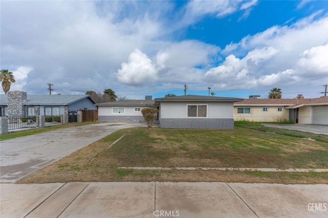 ranch-style house featuring fence, a front lawn, concrete driveway, and stucco siding