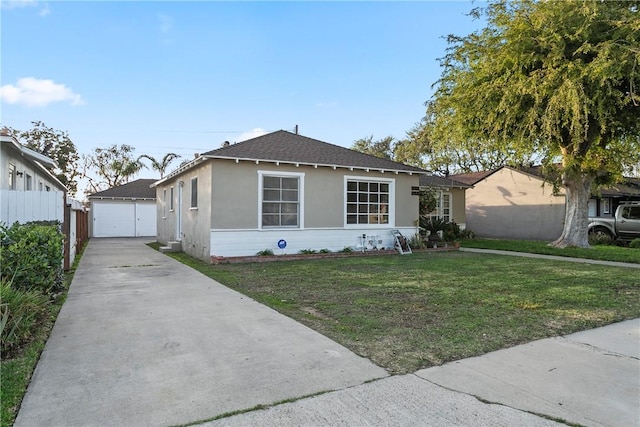 view of front of house featuring a detached garage, roof with shingles, fence, a front yard, and stucco siding