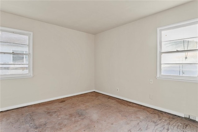 unfurnished room with concrete flooring, a healthy amount of sunlight, and baseboards