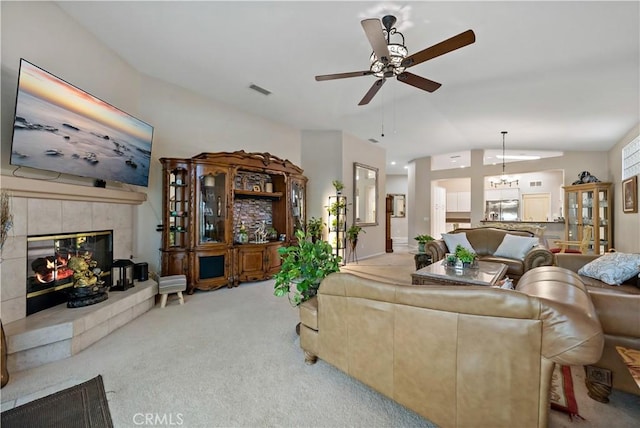 living area with a tile fireplace, light carpet, vaulted ceiling, and visible vents