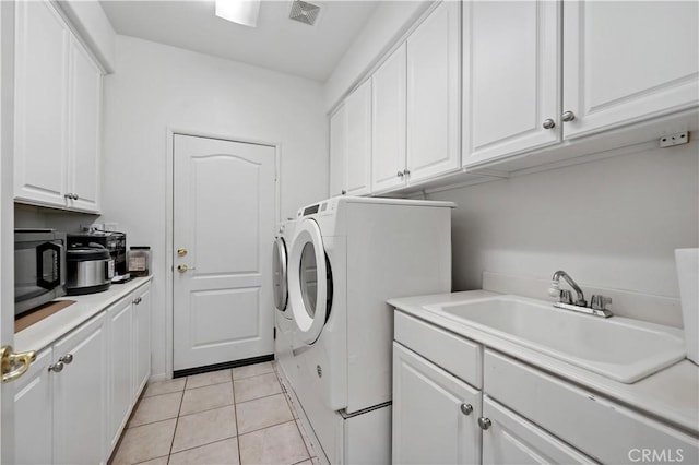 washroom featuring independent washer and dryer, visible vents, a sink, and light tile patterned floors