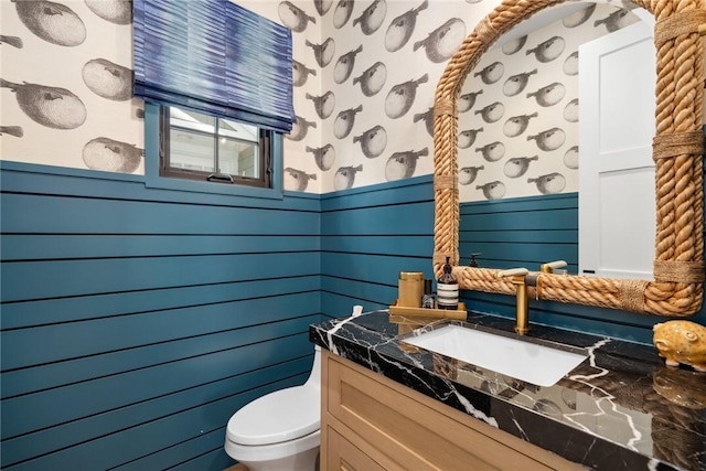 bathroom featuring toilet, a wainscoted wall, and vanity