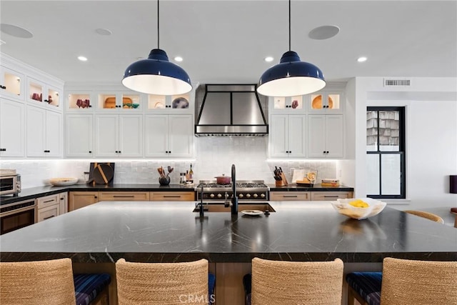 kitchen with premium range hood, glass insert cabinets, and a large island