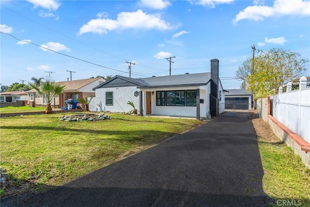 view of front of home with stucco siding, a chimney, fence, and a front yard