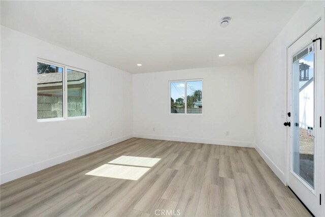 empty room with light wood finished floors, baseboards, and recessed lighting