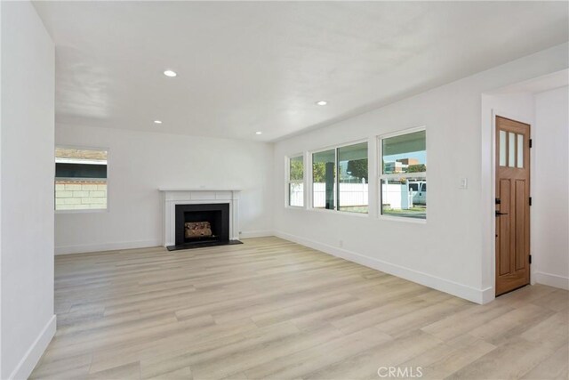 unfurnished living room featuring light wood finished floors, a fireplace with flush hearth, and recessed lighting