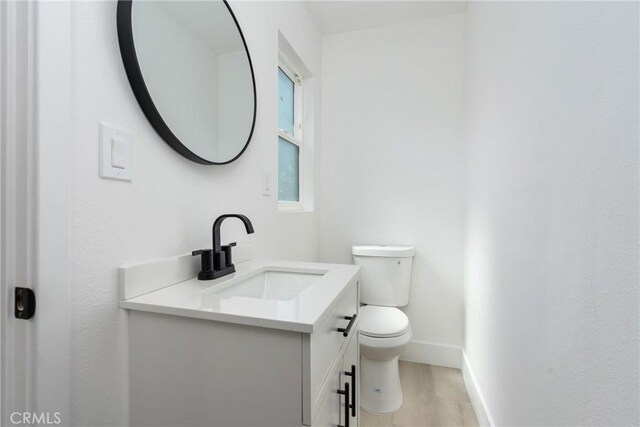 bathroom featuring wood finished floors, vanity, toilet, and baseboards