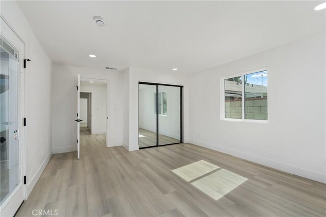 unfurnished bedroom featuring recessed lighting, a closet, light wood-style flooring, and baseboards