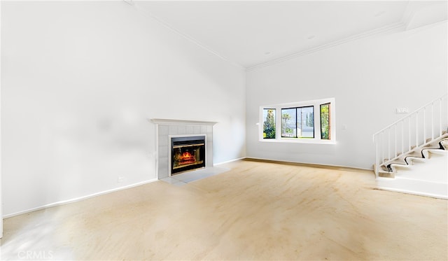 unfurnished living room with ornamental molding, stairway, a high ceiling, baseboards, and a tile fireplace