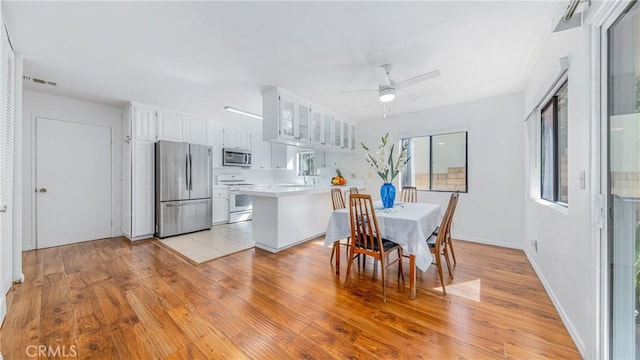 dining area with light wood-style flooring, baseboards, visible vents, and ceiling fan