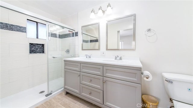 bathroom with double vanity, toilet, a stall shower, and a sink