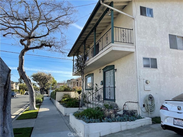 view of side of property featuring a balcony and stucco siding