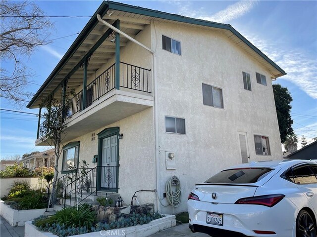 view of side of home featuring a balcony and stucco siding