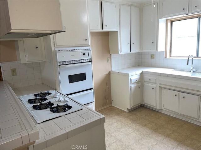 kitchen featuring a sink, white appliances, a warming drawer, and tile countertops